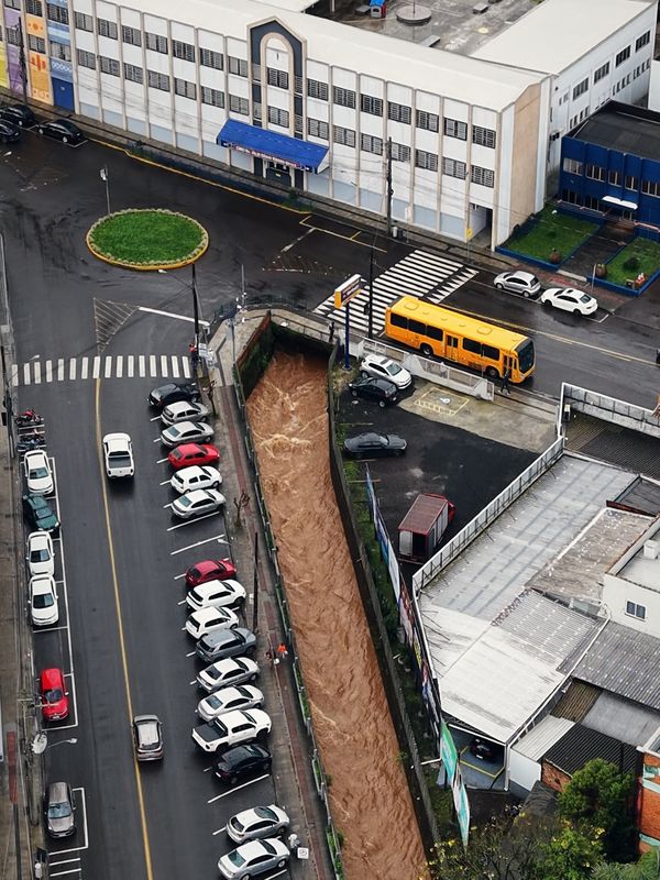 Rio cheio de água barrenta no canal ao lado das ruas do centro de Concórdia, visto de cima