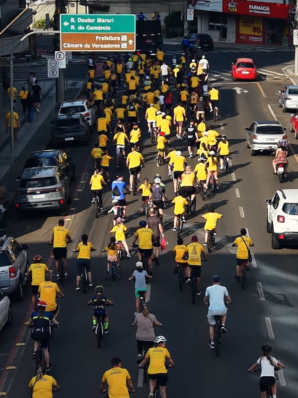 Passeio ciclístico com o pelotão de camisetas amarelas descendo o centro de Concórdia