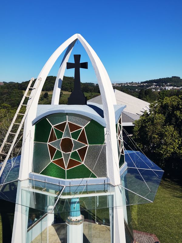 Campanário do Santuário da Salette com vitral e cruz contra o céu azul