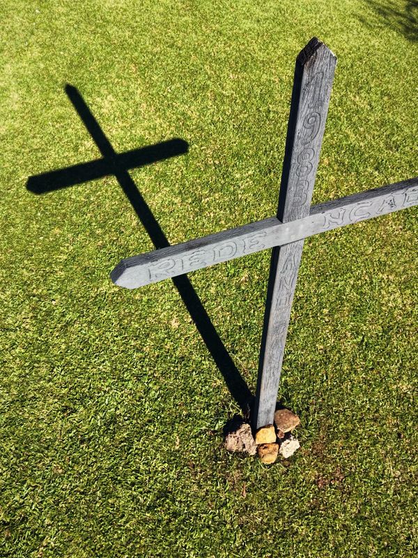 Cruz de madeira no gramado do Santuário da Salette e a sua sombra, vista do alto