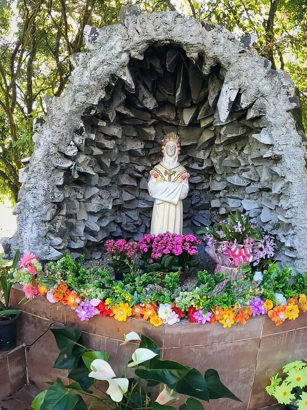 Gruta de pedra com a imagem de Nossa Senhora e flores no Santuário da Salette