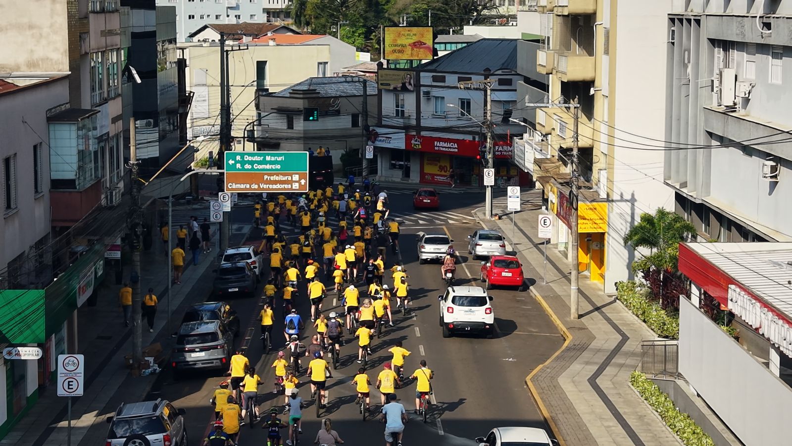Passeio ciclístico com centenas de ciclistas de camiseta amarela no centro de Concórdia, visto do alto